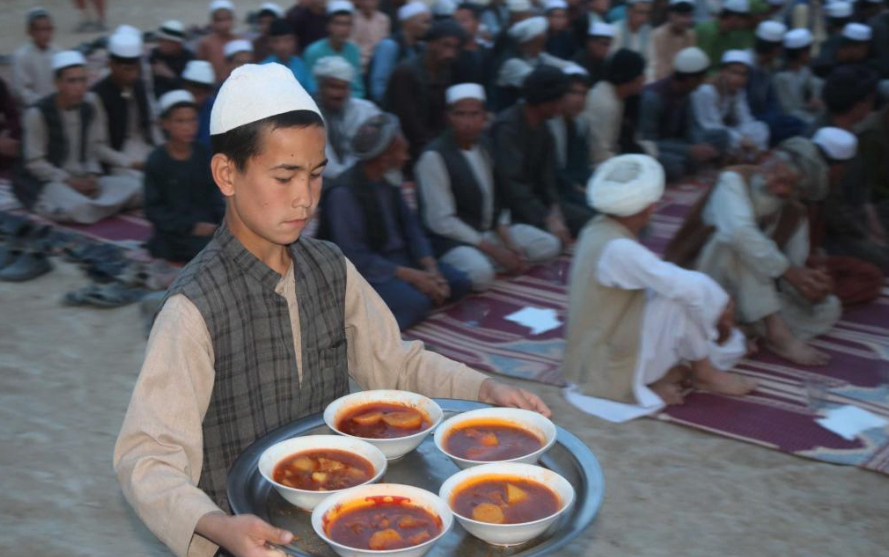 Image of a young boy carrying bowls of soup.